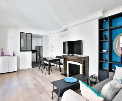 Salon moderne lumineux avec cuisine ouverte, cheminée, rangements intégrés bleus. Design contemporain pour appartement de luxe.