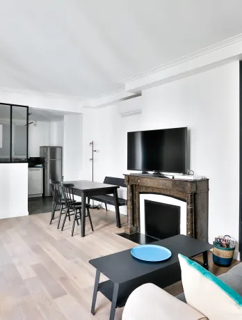 Salon moderne lumineux avec cuisine ouverte, cheminée, rangements intégrés bleus. Design contemporain pour appartement de luxe.