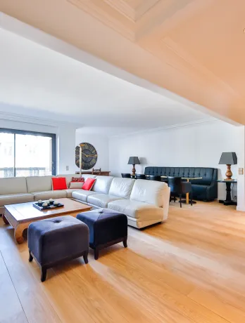 Salon de luxe spacieux et lumineux avec parquet clair, canapé sectionnel moderne, coin repas et bar intégré. Design contemporain haut de gamme.