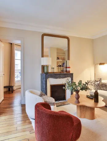 Salon parisien luxe, design moderne et élégant avec cheminée, parquet et lumière naturelle. Idéal pour un appartement haut de gamme.